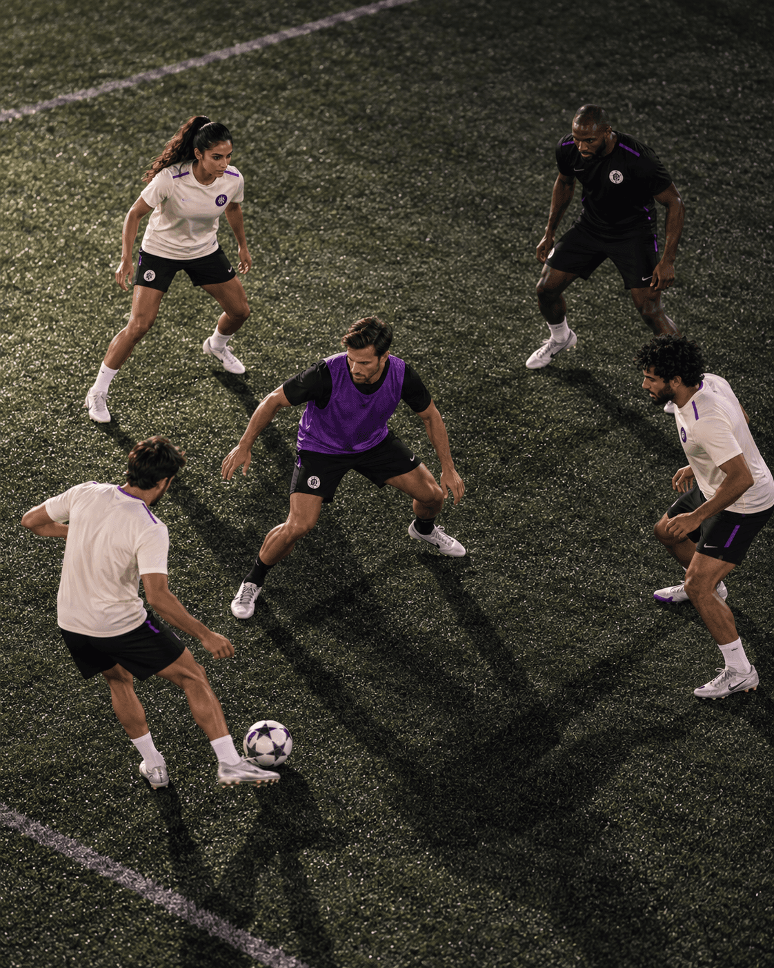 Players in a rondo passing drill with a player in a violet bib