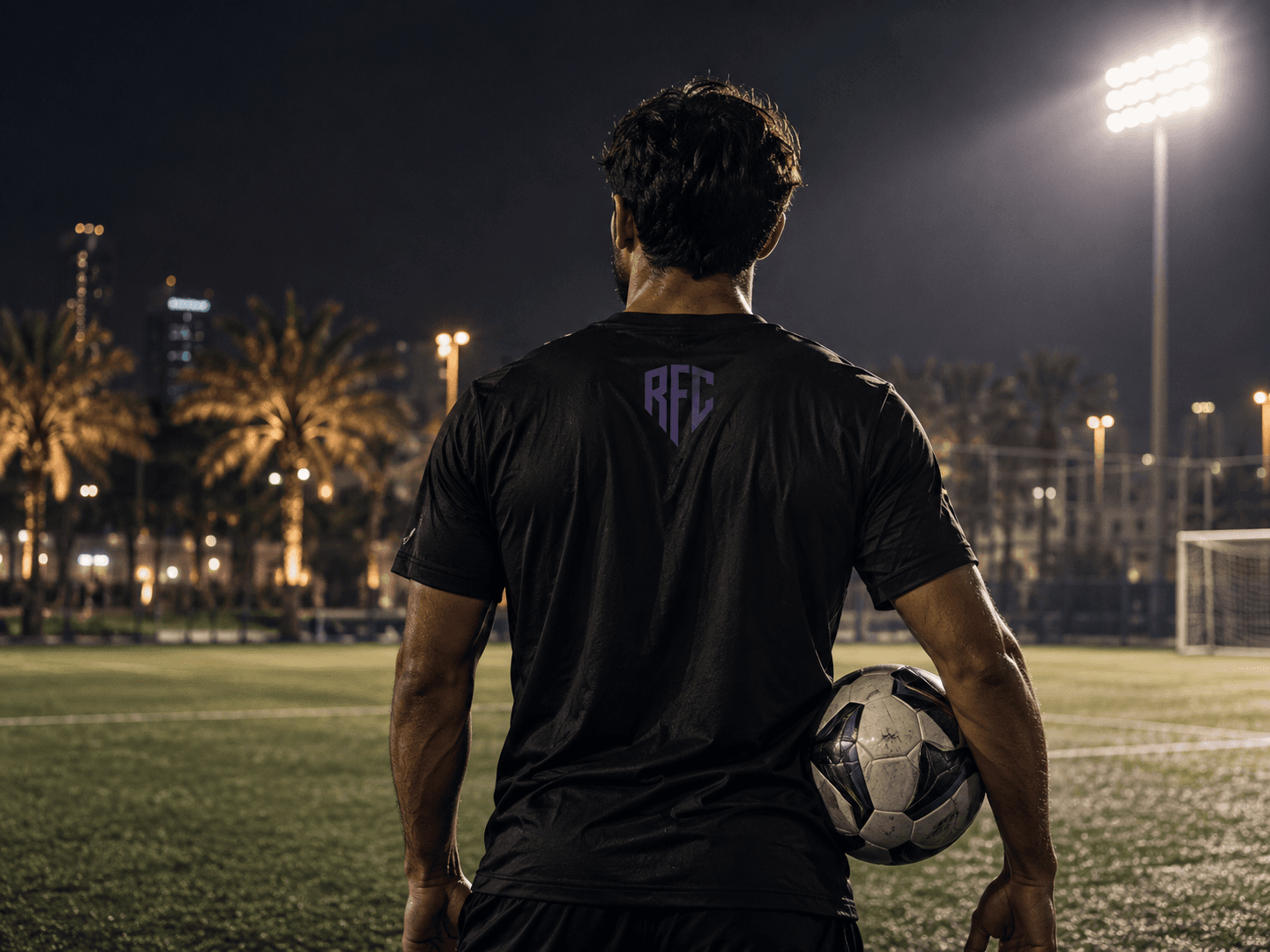 Rondo FC player with a ball under floodlights, seen from behind